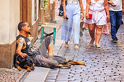 Ð¡ity landscape - view of a beggar sitting on a stone pavement in the Old Town of Prague Editorial Stock Photo